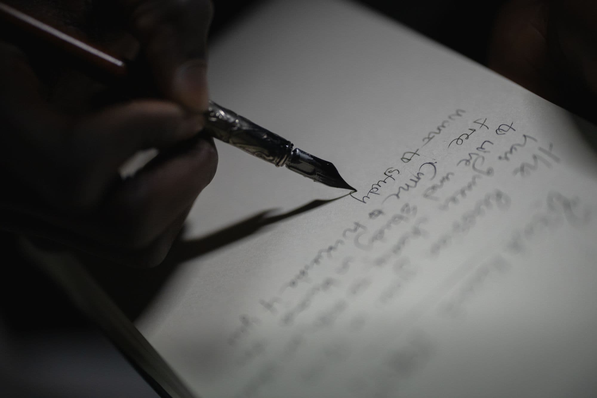 A hand writing a letter with a fountain pen